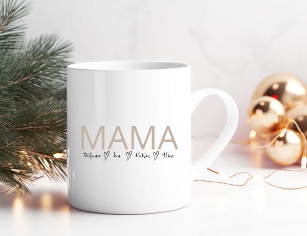 Weiße Keramiktasse mit dem Schriftzug 'MAMA' in großer, schlichter Schrift auf der Vorderseite. Darunter stehen die Namen 'Stefanie, Jan, Katrin, Alina' in feiner Handschrift, getrennt durch kleine Herzen. Die Tasse steht vor einer festlichen Kulisse mit
